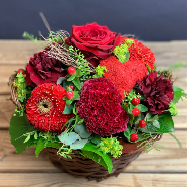 Panier fleuri dans les teintes rouge avec une coeur en sissal rouge. Des Lys & Délices, Sion