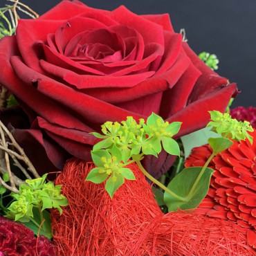 Panier fleuri dans les teintes rouge avec une coeur en sissal rouge. Des Lys & Délices, Sion