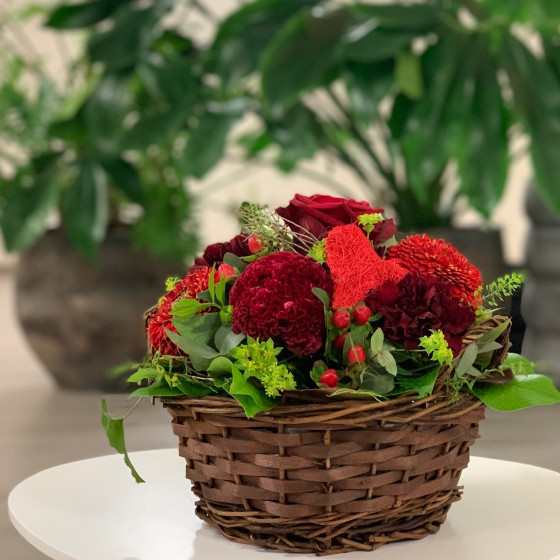 Panier fleuri dans les teintes rouge avec une coeur en sissal rouge. Des Lys & Délices, Sion